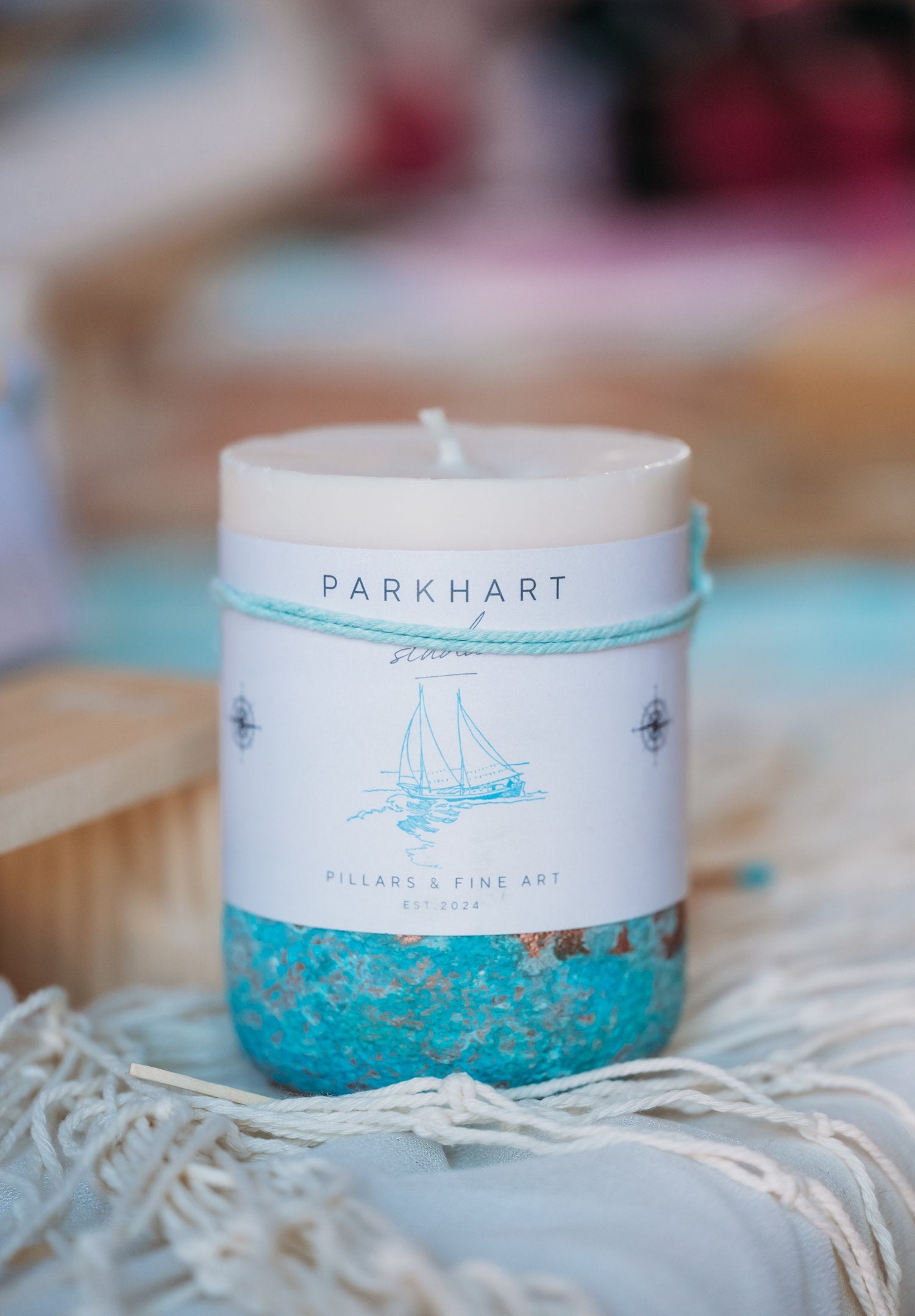 Luxury coastal beach candle with a 'Parkhart' label on a textured surface. The scent is coconut, banana, pineapple, vanilla, tonka bean
